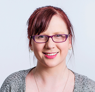 student with glasses and red hair smiling at camera