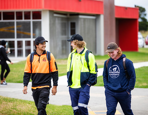 three male tradie students walking together within the campus